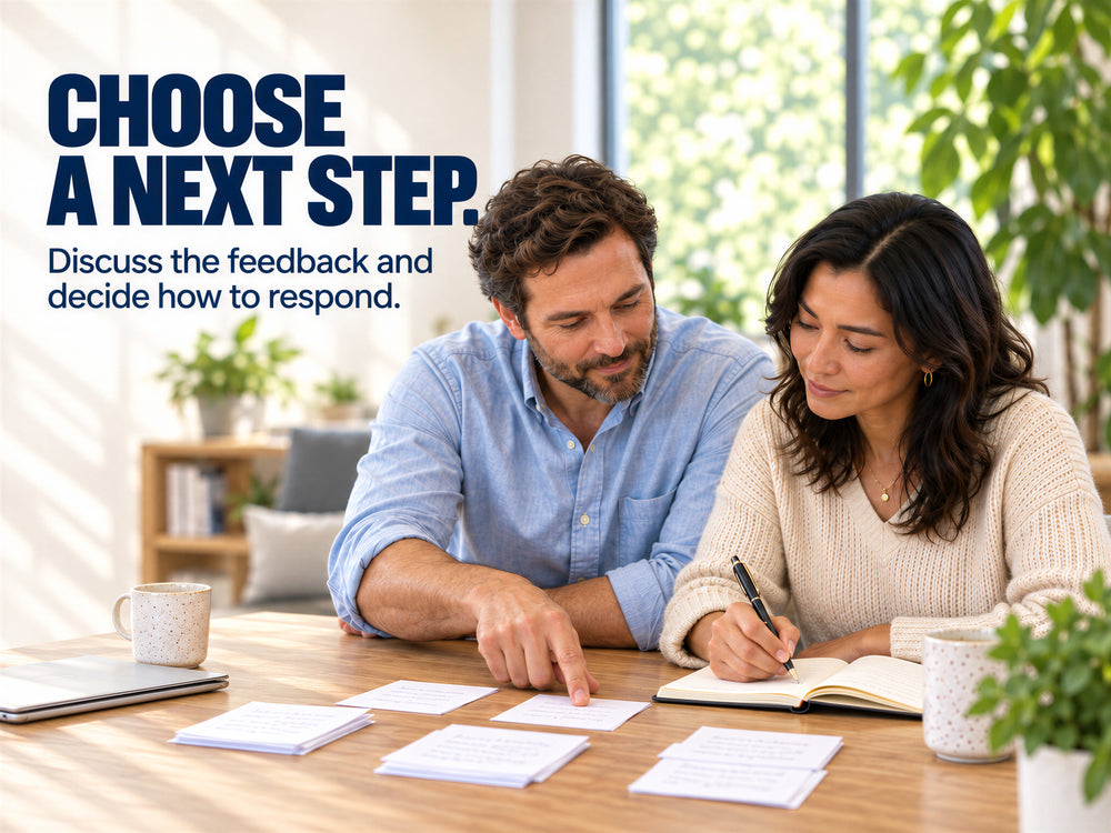 Two adults reviewing feedback cards and writing in a notebook.